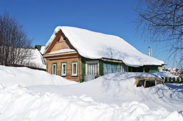 Houten huis en een auto in sneeuw driften — Stockfoto