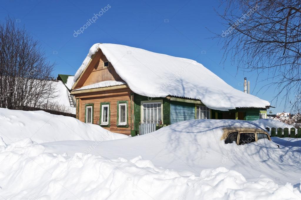 Wooden house and a car in snow drifts