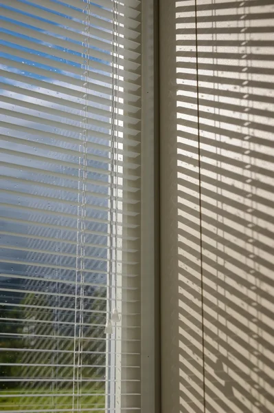 Sunlight after a storm breaks through the blinds — Stock Photo, Image