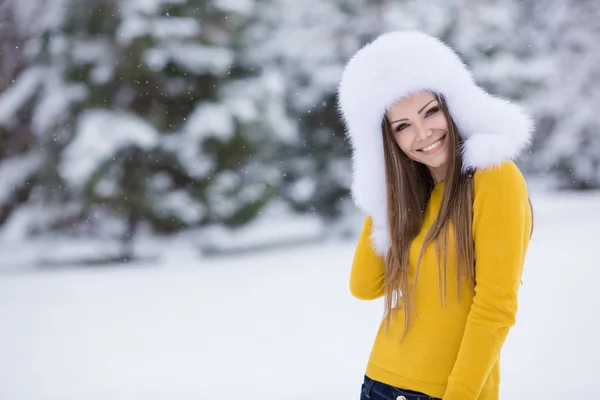 Schöne Mädchen mit einem weißen flauschigen Hut auf Schnee — Stockfoto