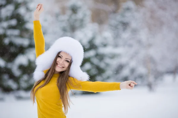 Hermosa chica en un sombrero blanco esponjoso en la nieve — Foto de Stock