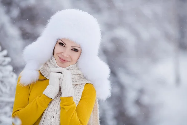 Hermosa chica en un sombrero blanco esponjoso en la nieve — Foto de Stock