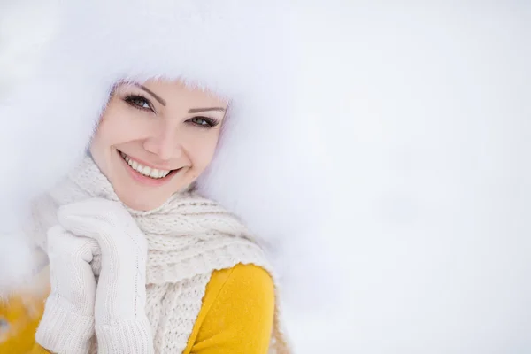 Schöne Mädchen mit einem weißen flauschigen Hut auf Schnee — Stockfoto