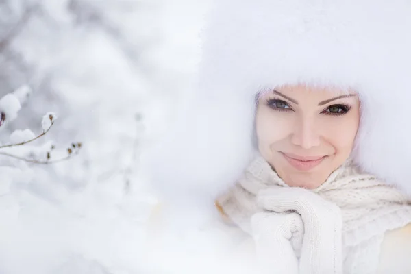 Beautiful girl in a white fluffy hat on snow — Stock Photo, Image