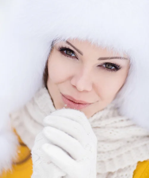 Schöne Mädchen mit einem weißen flauschigen Hut auf Schnee — Stockfoto