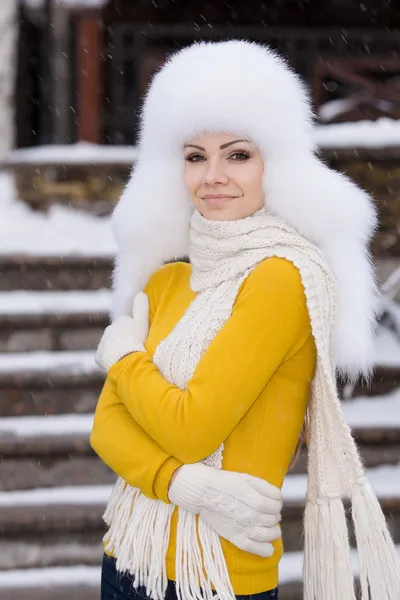 Mooi meisje in een witte pluizige hoed op sneeuw — Stockfoto