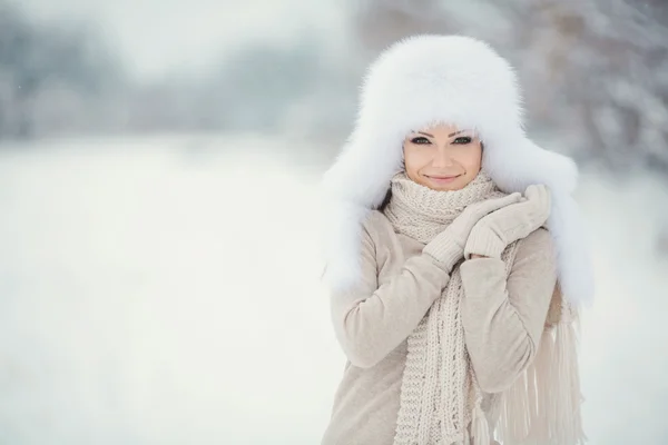 Schöne Mädchen mit einem weißen flauschigen Hut auf Schnee — Stockfoto