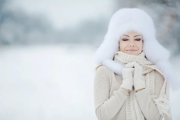 Mooi meisje in een witte pluizige hoed op sneeuw — Stockfoto