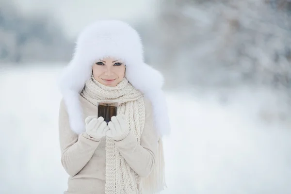 Beautiful girl in a white fluffy hat on snow — Stock Photo, Image