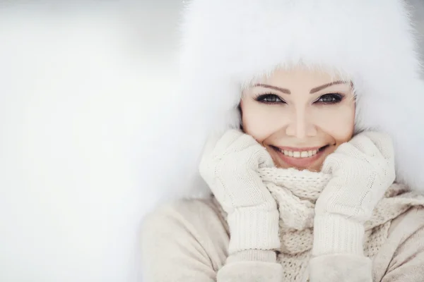 Hermosa chica en un sombrero blanco esponjoso en la nieve —  Fotos de Stock