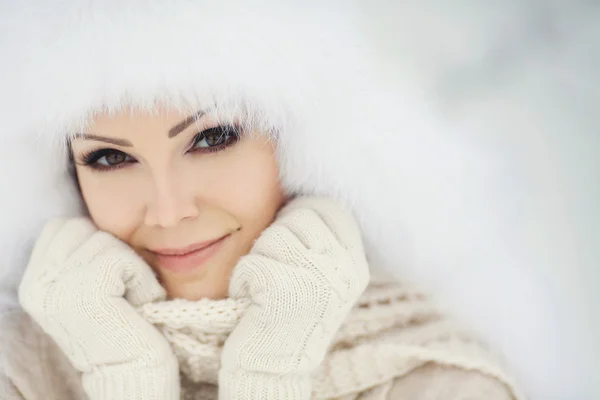 Beautiful girl in a white fluffy hat on snow — Stock Photo, Image