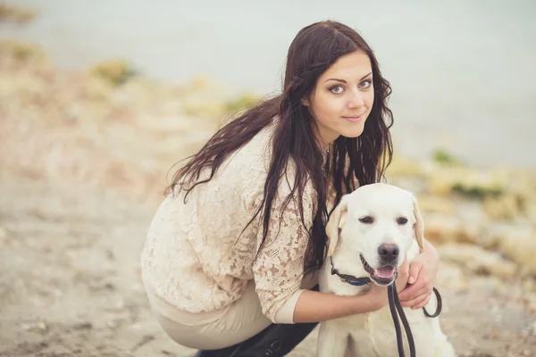 Porträtt av vacker ung kvinna leker med hunden på havet — Stockfoto