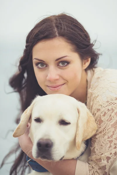 Portrait of beautiful young woman playing with dog on the sea — Stock Photo, Image