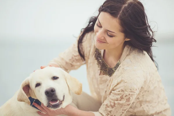 Portret van mooie jonge vrouw met hond spelen op de zee — Stockfoto