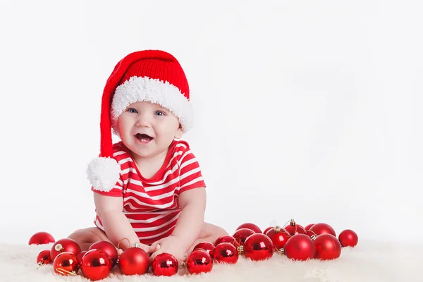 Adorable child in santa cap with stacks of present boxes around — Stock Photo, Image