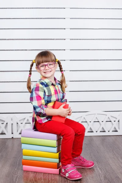 Маленькая девочка сидит на стопке книг — стоковое фото