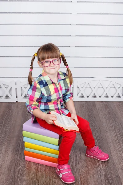 Niña sentada en una pila de libros — Foto de Stock