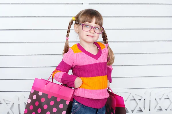 Vista lateral de la mujer sosteniendo bolsas de compras sobre fondo blanco —  Fotos de Stock