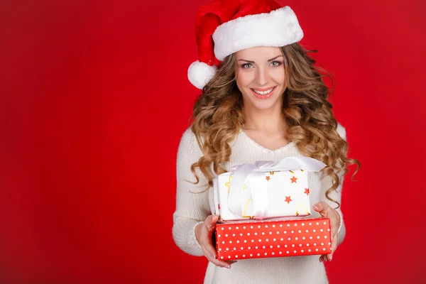 Woman wrapping christmas presents wearing santa hat. Royalty Free Stock Photos