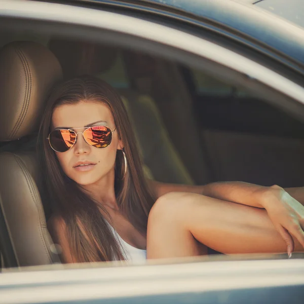 Portrait of beautiful sexy fashion woman model with bright makeup sitting in a car — Stock Photo, Image