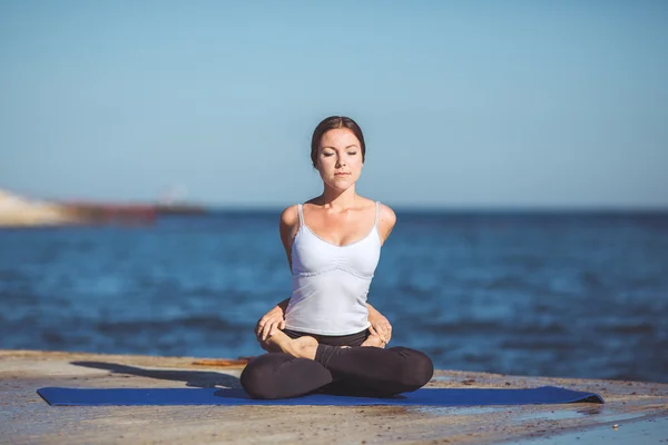 Genç kadın, deniz kıyısında, yoga egzersizleri — Stok fotoğraf