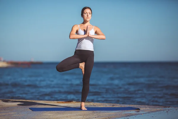 Genç kadın, deniz kıyısında, yoga egzersizleri — Stok fotoğraf
