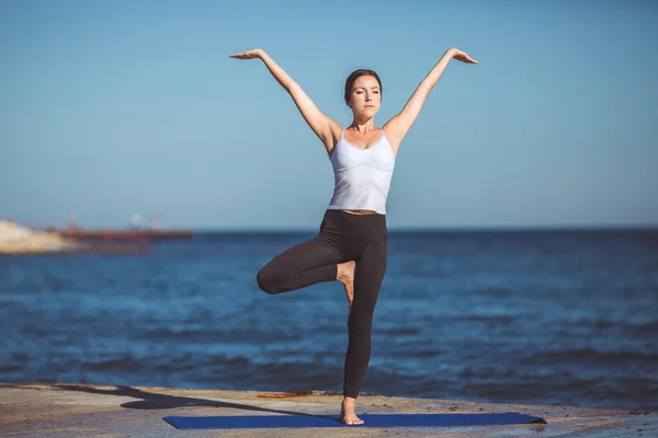 Genç kadın, deniz kıyısında, yoga egzersizleri — Stok fotoğraf