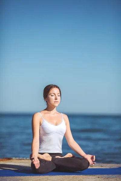 Genç kadın, deniz kıyısında, yoga egzersizleri — Stok fotoğraf