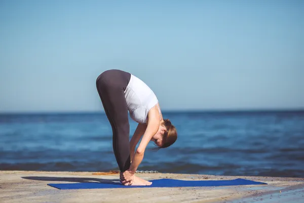 Genç kadın, deniz kıyısında, yoga egzersizleri — Stok fotoğraf