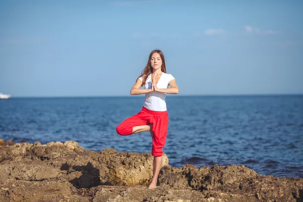 Mujer joven, orilla del mar, ejercicios de yoga —  Fotos de Stock