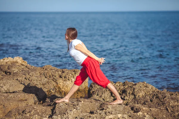 Genç kadın, deniz kıyısında, yoga egzersizleri — Stok fotoğraf