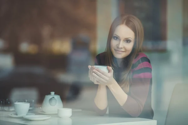 Mujer joven y bonita sentada en un café con una taza de té —  Fotos de Stock