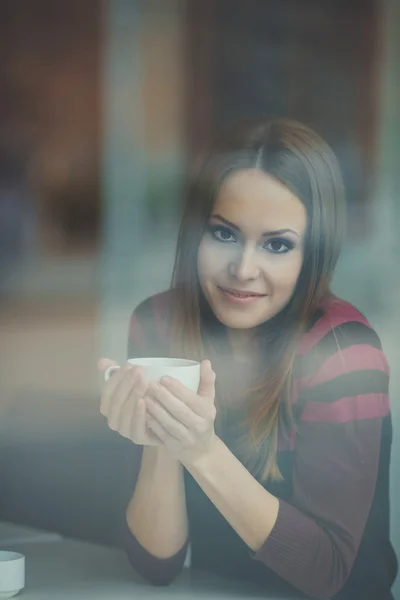 Красивая молодая женщина сидит в кафе с чашкой чая — стоковое фото