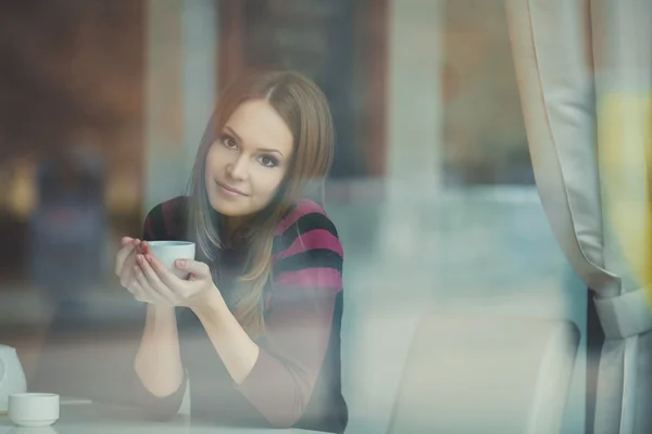 Jolie jeune femme assise dans un café avec une tasse de thé — Photo