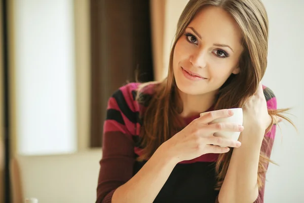 Mujer joven y bonita sentada en un café con una taza de té —  Fotos de Stock