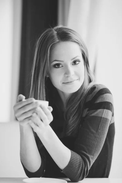 Pretty young woman sitting in a cafe with a cup of tea — Stock Photo, Image