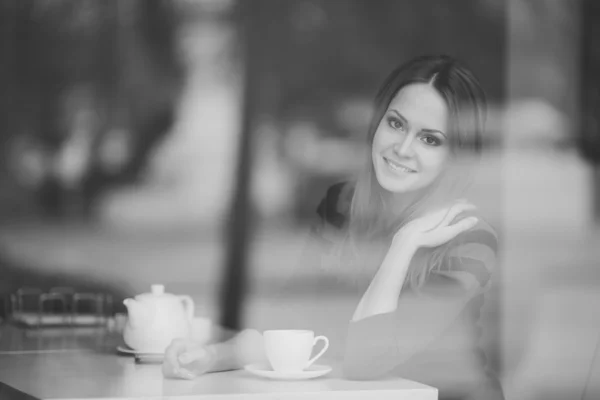 Pretty young woman sitting in a cafe with a cup of tea — Stock Photo, Image