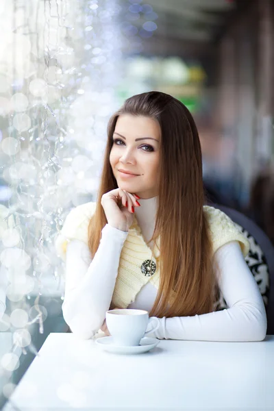 Hübsche junge Frau sitzt mit einer Tasse Kaffee im Café — Stockfoto
