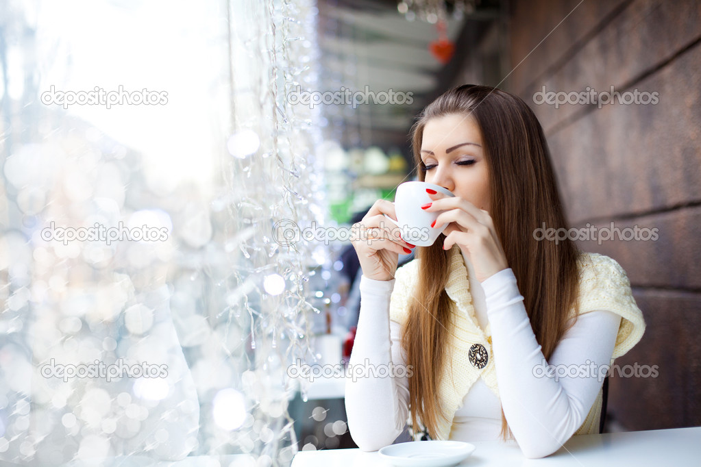 Pretty young woman sitting in the cafe with a cup of coffee
