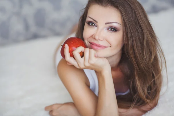 Joven hermosa mujer con manzana en la cama por la mañana — Foto de Stock