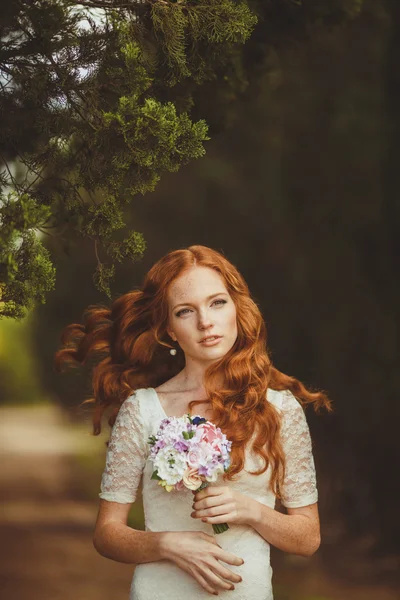 Портрет молодой красивой рыжей женщины, стоящей в зеленом летнем парке — стоковое фото