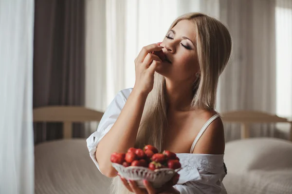 Mujer joven acostada en la cama con fresa —  Fotos de Stock