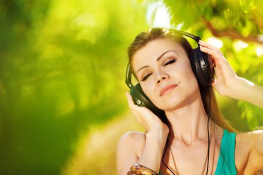 güzel bir genç kadın açık kulaklıklar giyen müzik dinlemek