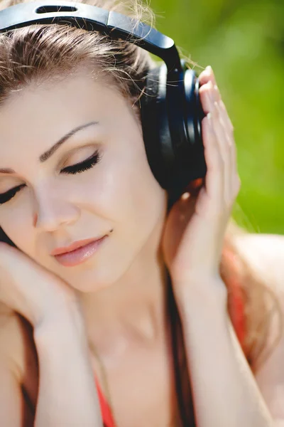 Piękna młoda kobieta słuchać muzyki noszenie słuchawek na zewnątrz — Zdjęcie stockowe