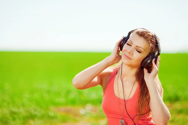 Belle jeune femme écouter de la musique portant des écouteurs à l'extérieur — Photo