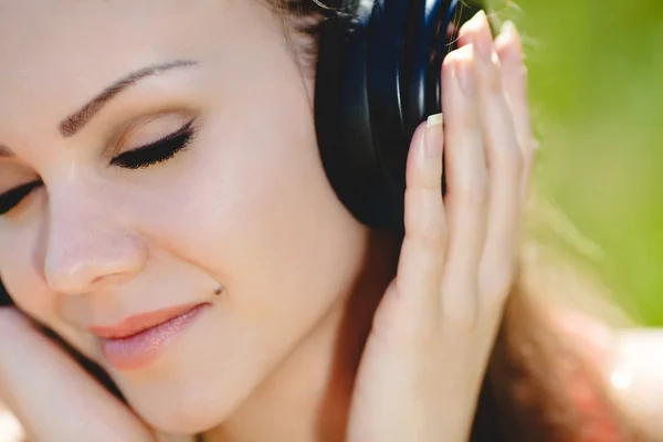 Güzel bir genç kadın açık havada kulaklıklar giyen müzik dinlemek — Stok fotoğraf