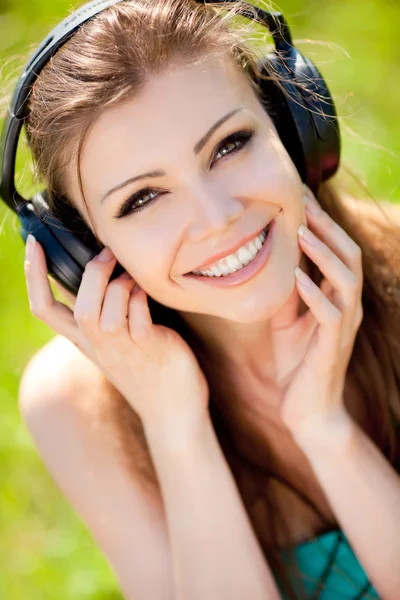 Beautiful young woman listen to music wearing headphones outdoors — Stock Photo, Image