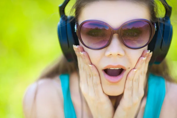 Wanita muda yang cantik mendengarkan musik memakai headphone di luar ruangan — Stok Foto