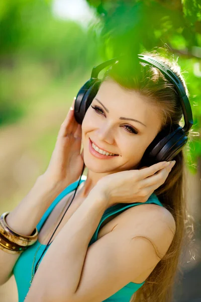 Mulher bonita ouvir música usando fones de ouvido ao ar livre — Fotografia de Stock