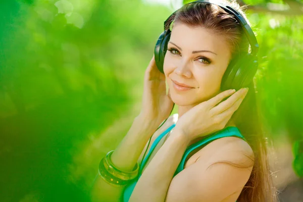 Piękna młoda kobieta słuchać muzyki noszenie słuchawek odkryty — Zdjęcie stockowe